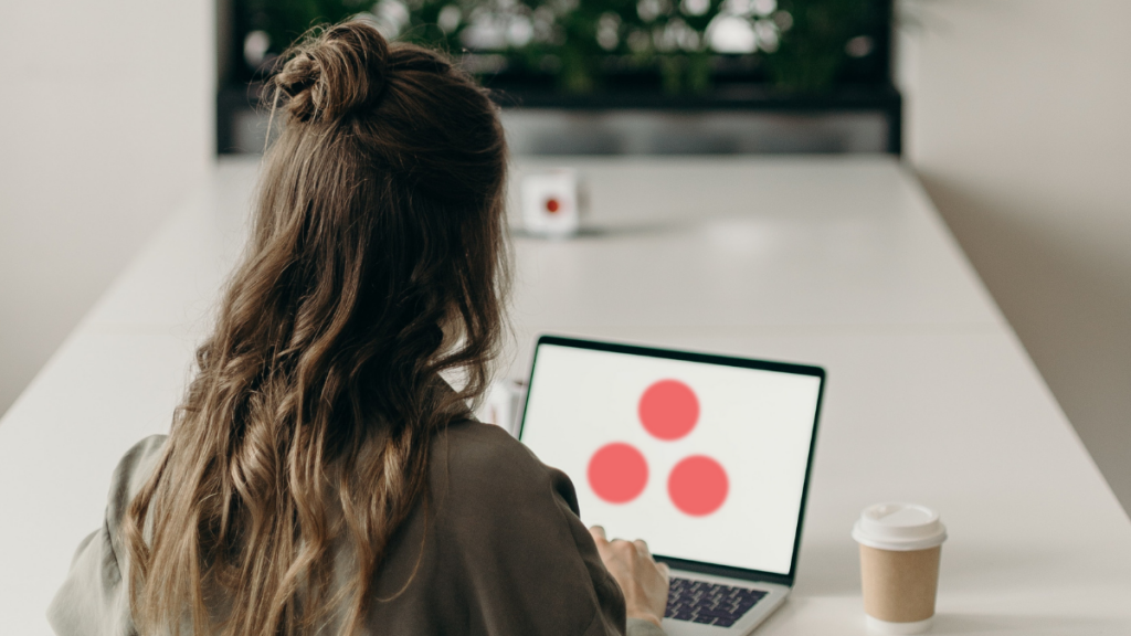 woman sitting at desk working on computer with asana open. asana plans on adding an ai tool to its app