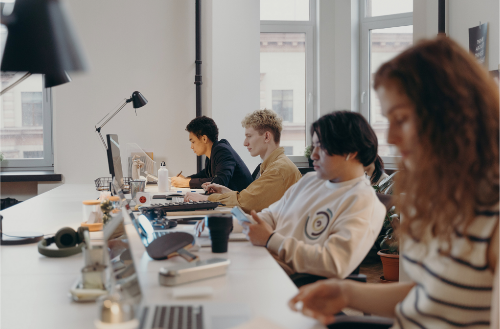 cohere's ai versus microsoft and ibm watson. photo is of four coworkers all using computers at their job