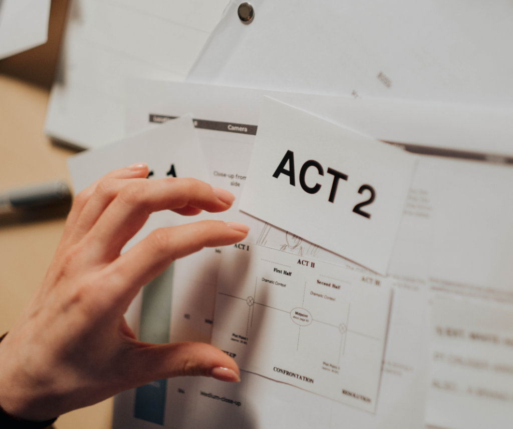 hand on top of papers with script instructions and large page saying "act 2" digital storytelling