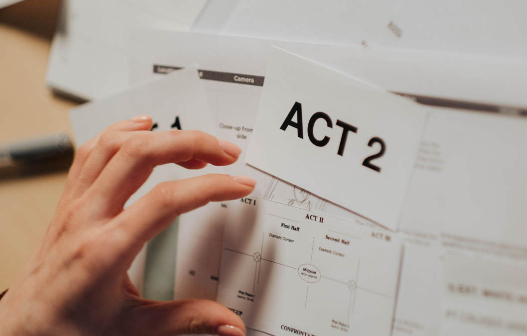 hand on top of papers with script instructions and large page saying "act 2" digital storytelling